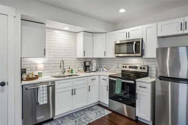 a kitchen with stainless steel appliances a stove sink microwave refrigerator and cabinets