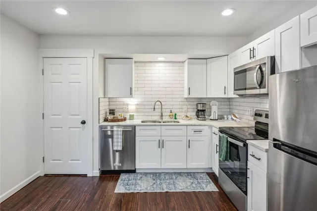 a kitchen with stainless steel appliances a sink cabinets and wooden floor