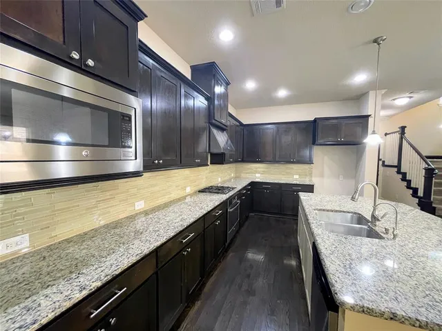 a kitchen with stainless steel appliances granite countertop sink stove and refrigerator
