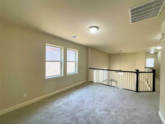an empty room with a chandelier fan and windows