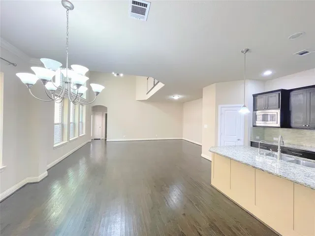 a view of a kitchen with granite countertop a sink dishwasher a stove and a wooden floors