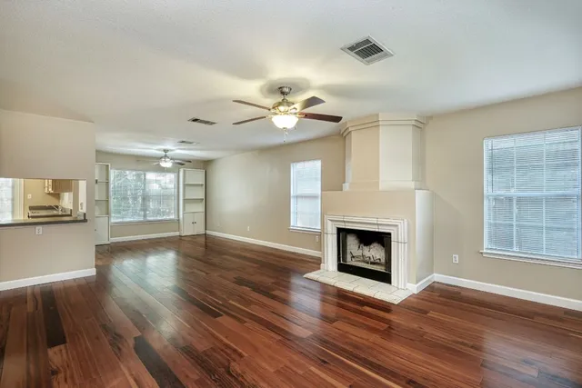a view of an empty room with wooden floor fireplace and a window