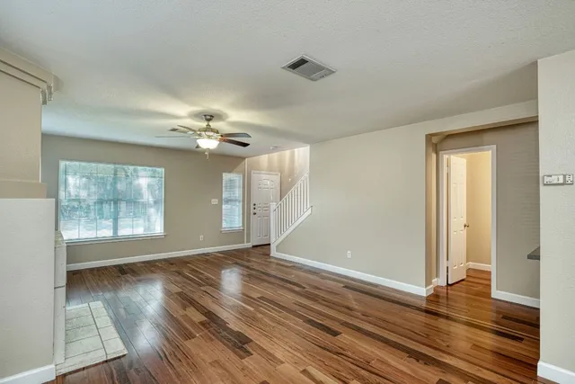 a view of an empty room with wooden floor and a window