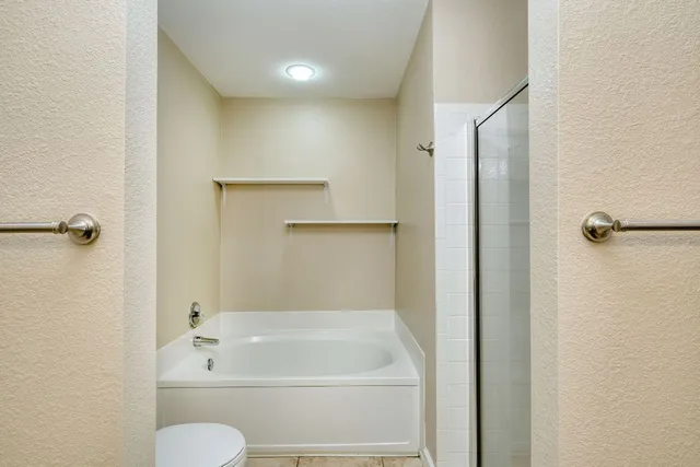 a bathroom with a shower a bathtub and a toilet