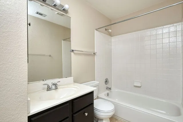 a bathroom with a bathtub shower sink vanity mirror and toilet