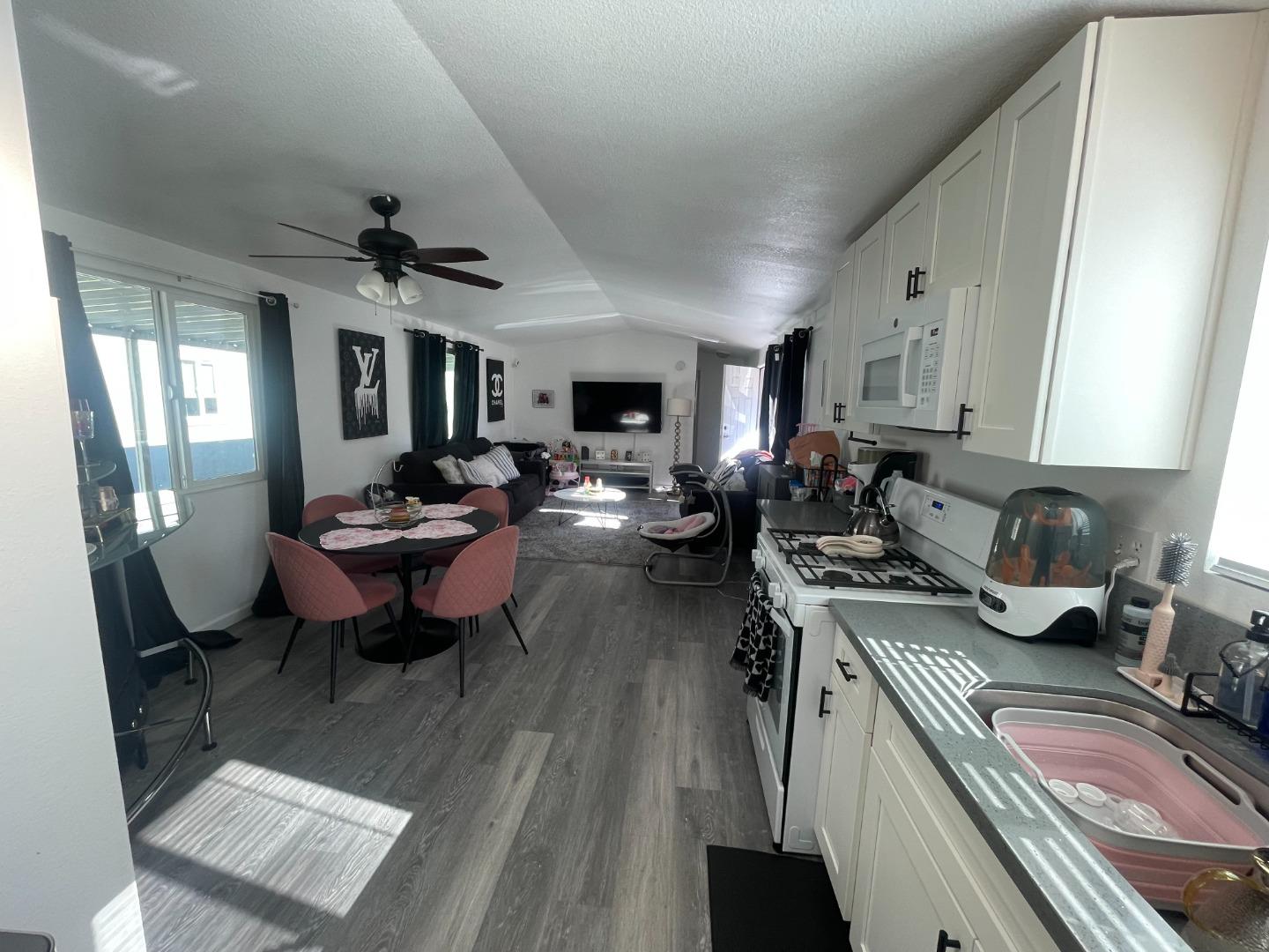a open kitchen with stainless steel appliances granite countertop a sink dishwasher stove a table and chairs with wooden floor