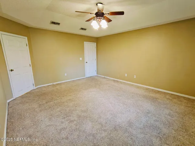 an empty room with windows and chandelier fan