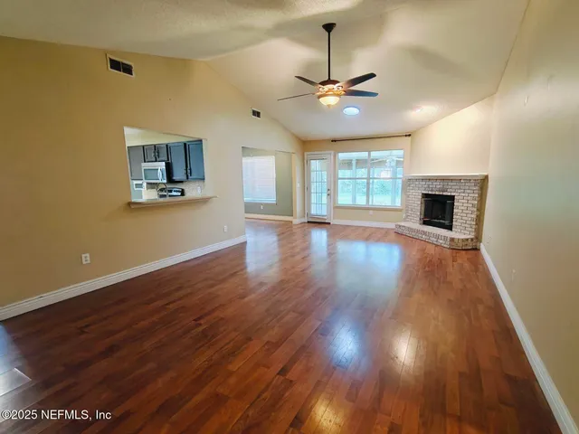 a view of a room with wooden floor fireplace and window