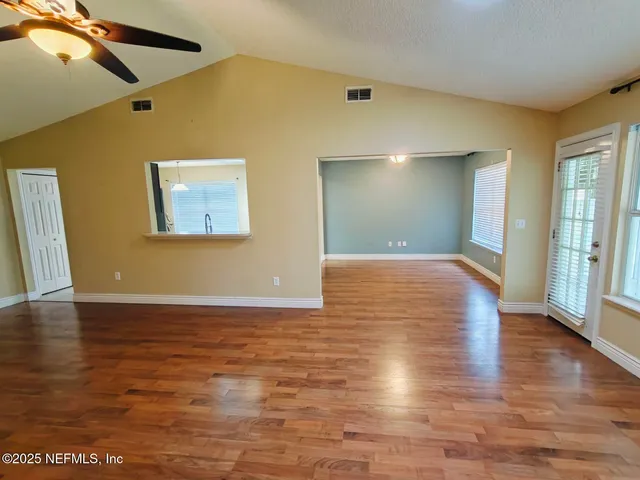 a view of a big room with wooden floor and windows