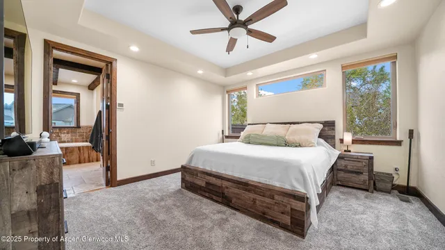 a spacious bedroom with a bed a dresser and a chandelier