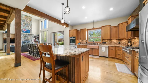 a open kitchen with stainless steel appliances kitchen island granite countertop a table chairs and a refrigerator