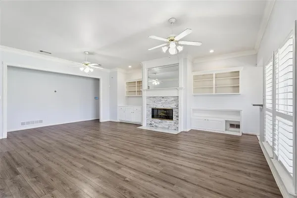 a view of a livingroom with a fireplace a ceiling fan and wooden floor