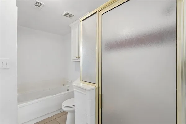 a bathroom with a granite countertop bathtub shower sink vanity and toilet