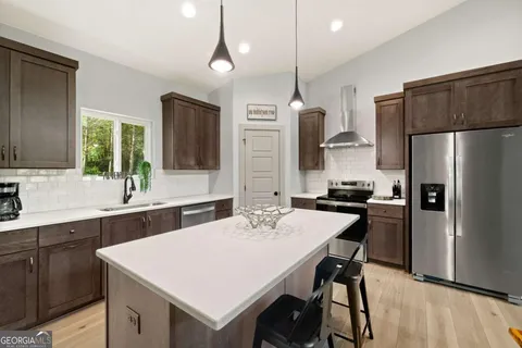 a kitchen with a refrigerator a sink a stove and chairs