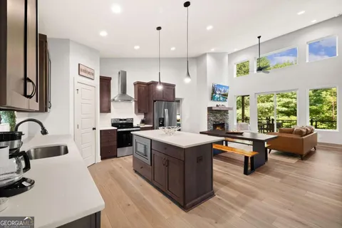 a open kitchen with stainless steel appliances granite countertop a stove refrigerator and a sink with wooden floor