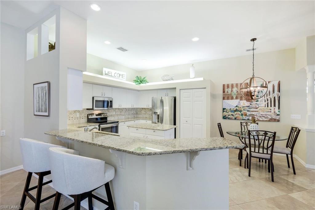10215 Cape Roman Road, Unit 101 Estero, FL 34135 - Photo 11 of 50 a kitchen with center island table and chairs