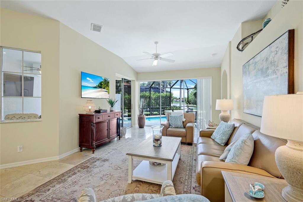 10215 Cape Roman Road, Unit 101 Estero, FL 34135 - Photo 5 of 50 a living room with furniture a floor to ceiling window and a flat screen tv
