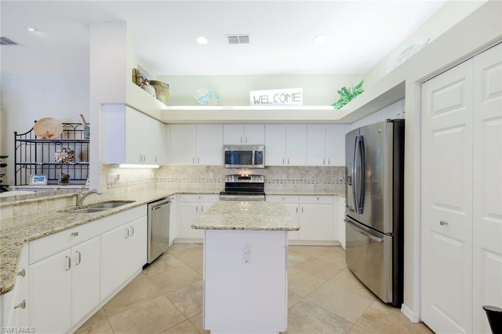 10215 Cape Roman Road, Unit 101 Estero, FL 34135 - Photo 8 of 50 a kitchen with stainless steel appliances granite countertop a refrigerator and a sink