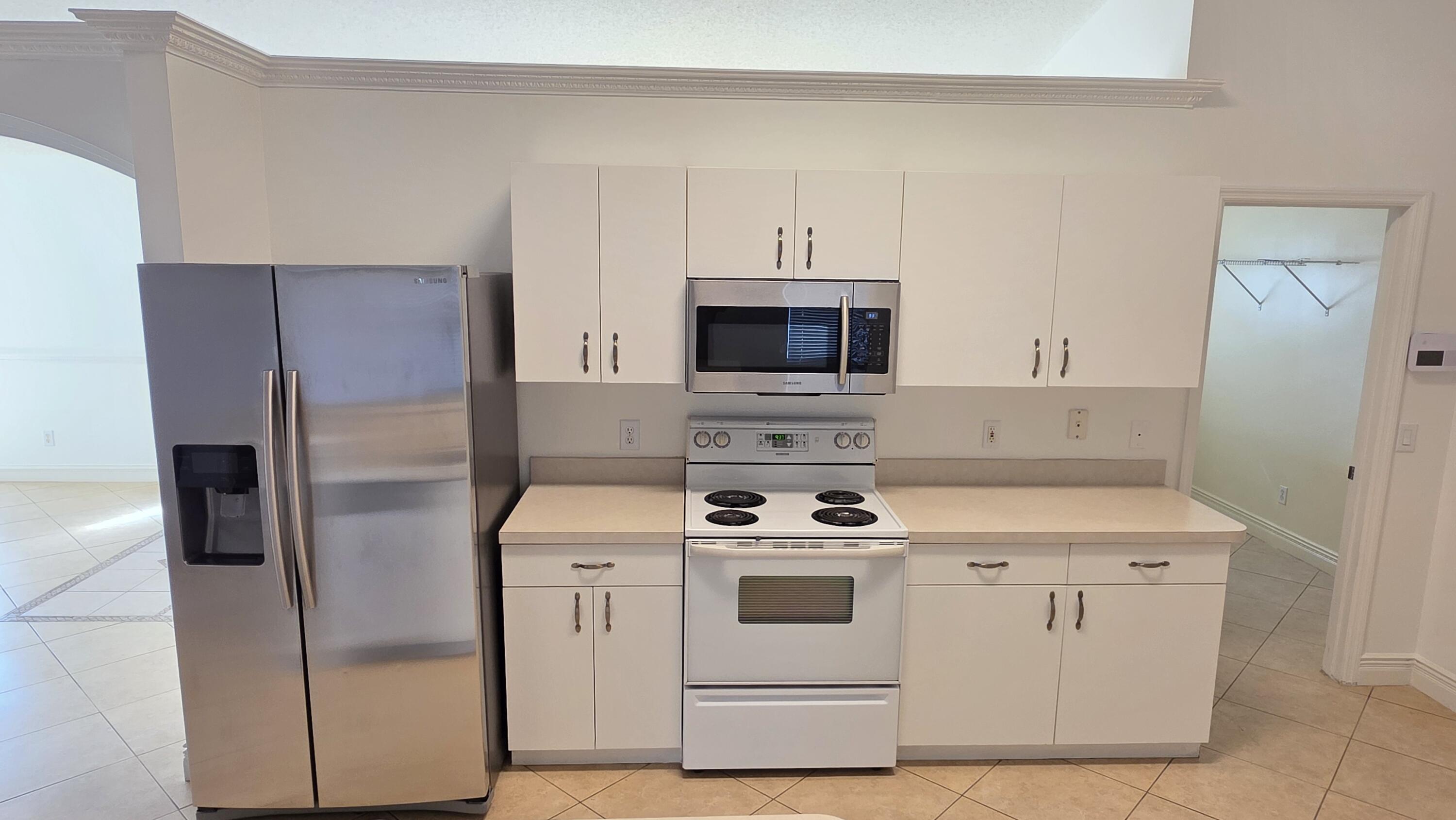 6448 Northwest Colgate Street Port St. Lucie, FL 34986 - Photo 7 of 21 a kitchen with stainless steel appliances white cabinets and a refrigerator