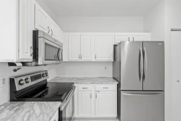 a view of a refrigerator in kitchen with stainless steel appliances wooden floor