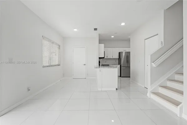 a view of kitchen with white cabinets and refrigerator
