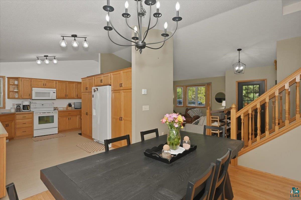 47 Amy Lane Esko, MN 55733 - Photo 12 of 33 Open-concept living space featuring a black dining table, light wood cabinetry in the kitchen, a white range, and a white refrigerator