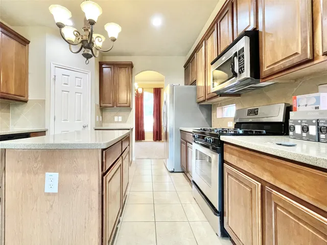 a view of an empty room with chandelier fan and fire place