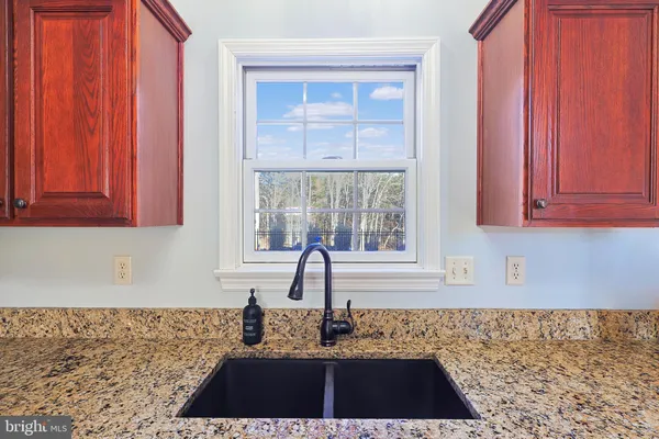 a kitchen with granite countertop a sink dishwasher stove and cabinets