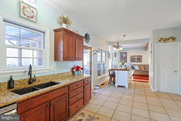 a kitchen with stainless steel appliances granite countertop a stove a sink dishwasher and white cabinets with wooden floor