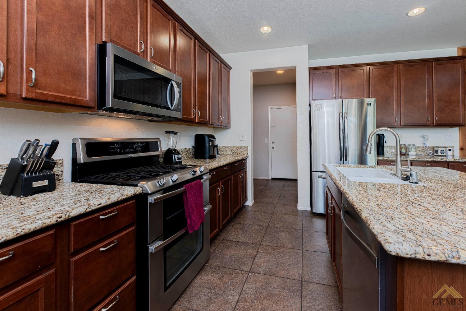 Undisclosed Address Bakersfield, CA 93314 - Photo 15 of 49 a kitchen with stainless steel appliances granite countertop wooden cabinets a stove a sink and a microwave