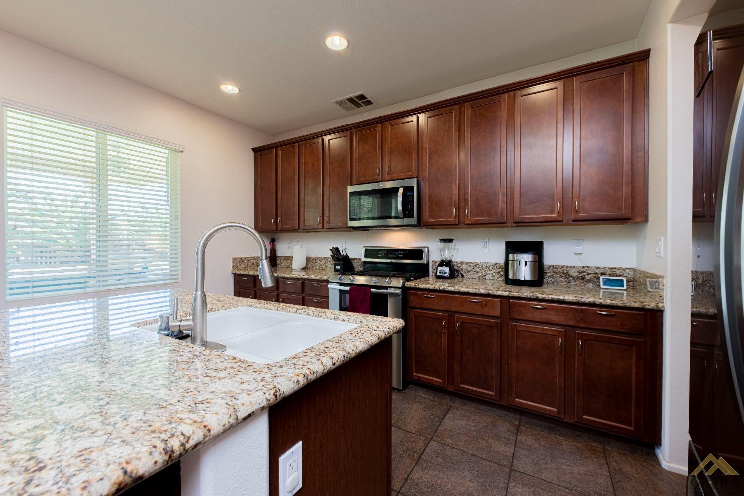 Undisclosed Address Bakersfield, CA 93314 - Photo 17 of 49 a kitchen with granite countertop a sink a stove and cabinets
