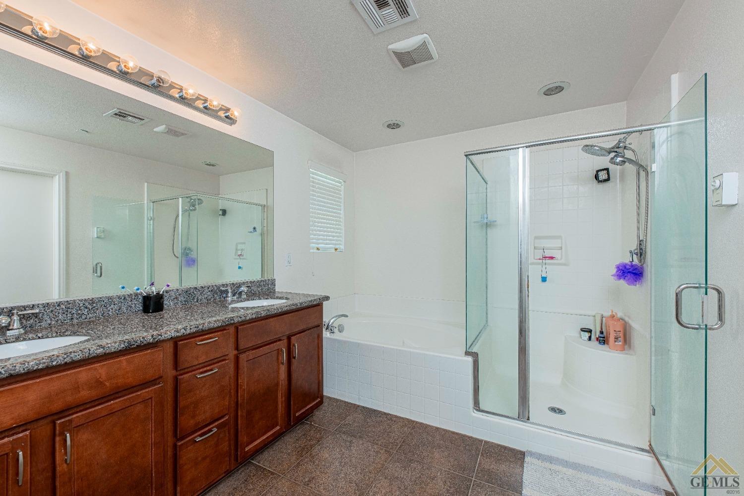 Undisclosed Address Bakersfield, CA 93314 - Photo 21 of 49 a spacious bathroom with a granite countertop sink mirror and shower
