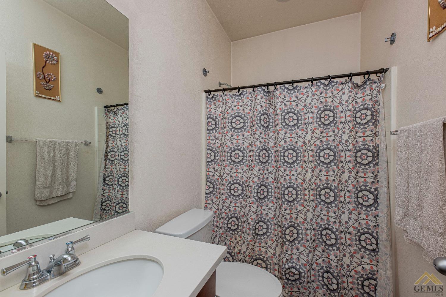 Undisclosed Address Bakersfield, CA 93314 - Photo 34 of 49 a bathroom with a toilet a sink and a shower curtain