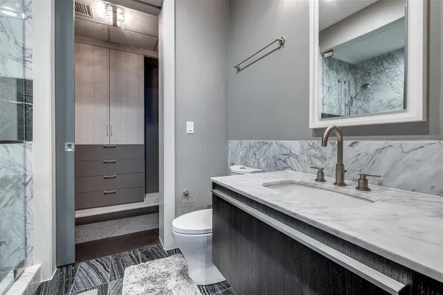 a bathroom with a granite countertop sink a toilet and mirror
