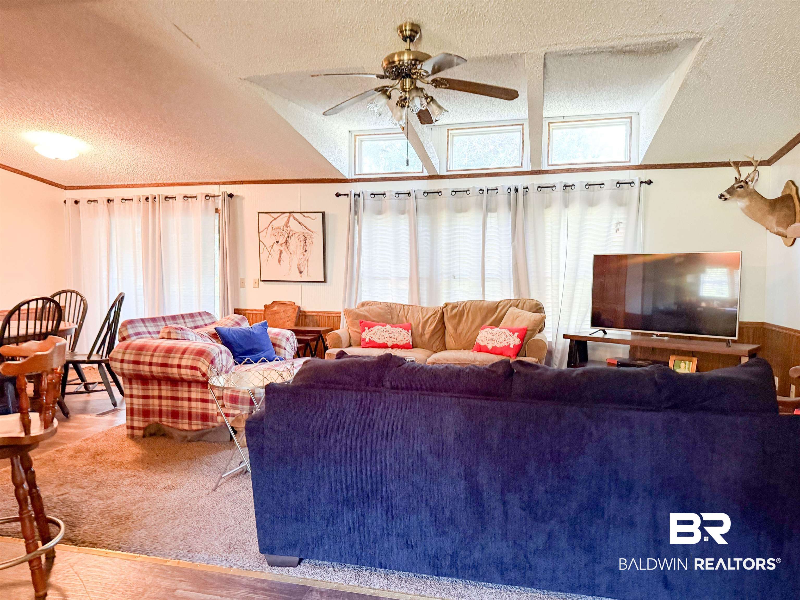 3346 Hoomesville Road Brewton, AL 36426 - Photo 9 of 16 Living room featuring ornamental molding, a textured ceiling, a ceiling fan, wainscoting, and wood walls