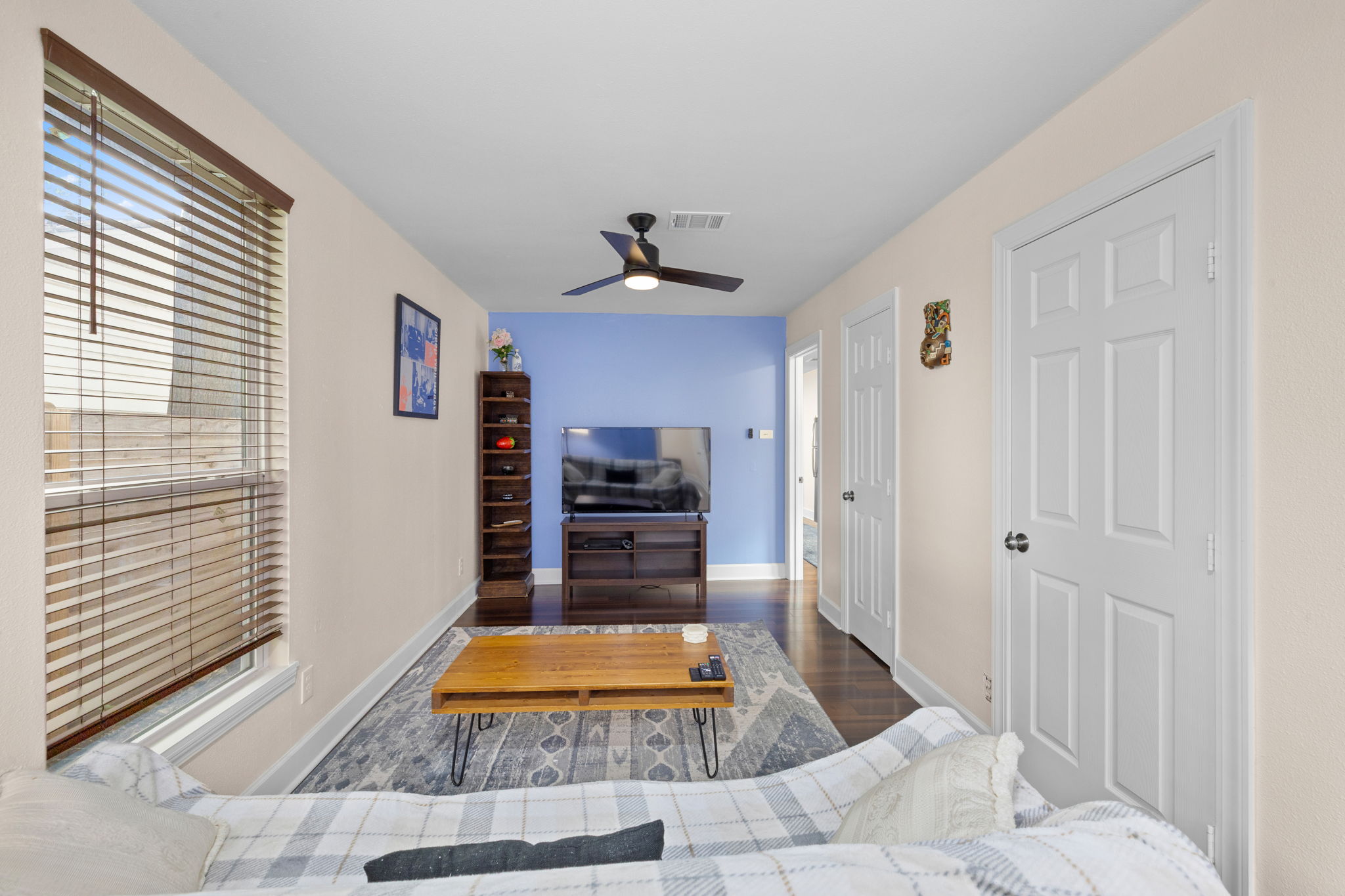 907 East 53rd Street Austin, TX 78751 - Photo 19 of 36 Hardwood flooring extends throughout this well-lit living area, highlighted by a modern ceiling fan.