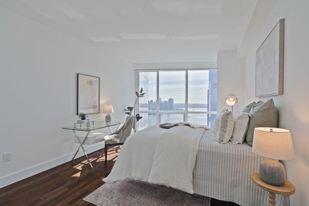 77 Hudson Street, Unit PH 4505 Jersey City, NJ 07302 - Photo 16 of 37 a room with a bed a lamp and window