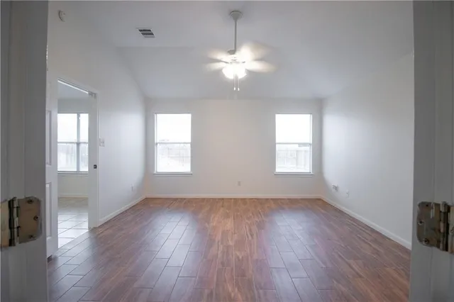 a view of an empty room with wooden floor and a window