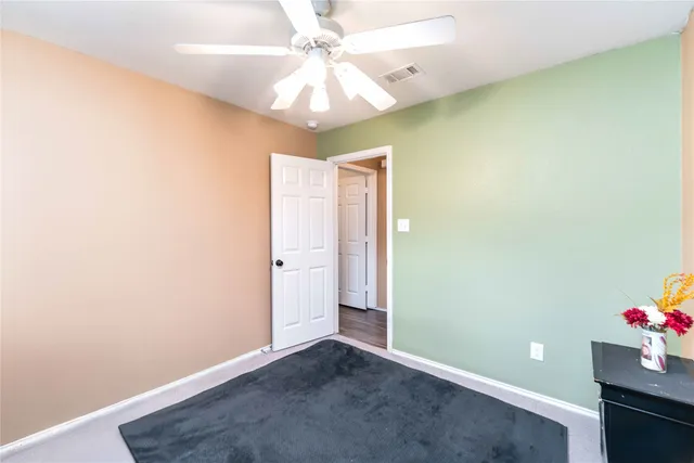 an empty room with a chandelier fan and closet