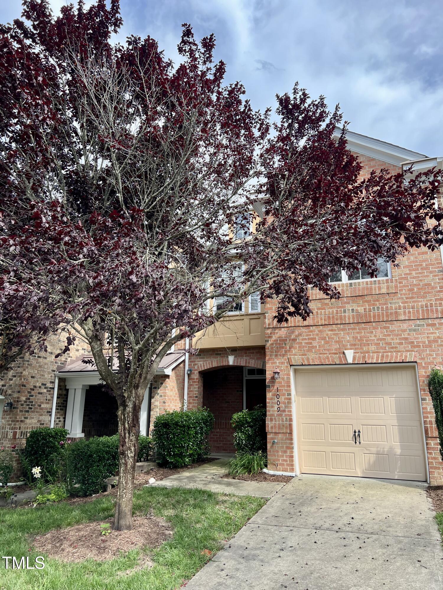 a front view of a house with a garden and trees