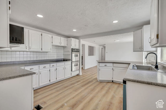 1472 South Hogans Road Stockton, UT 84071 - Photo 1 of 1 Kitchen with a textured ceiling, white cabinets, backsplash, light wood-style flooring, and recessed lighting
