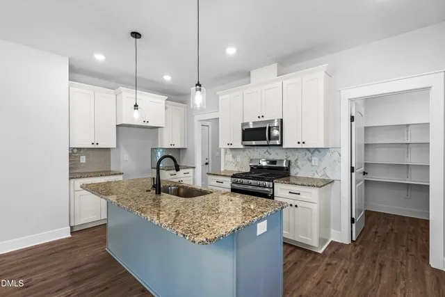 a kitchen with granite countertop a sink a counter space appliances and cabinets
