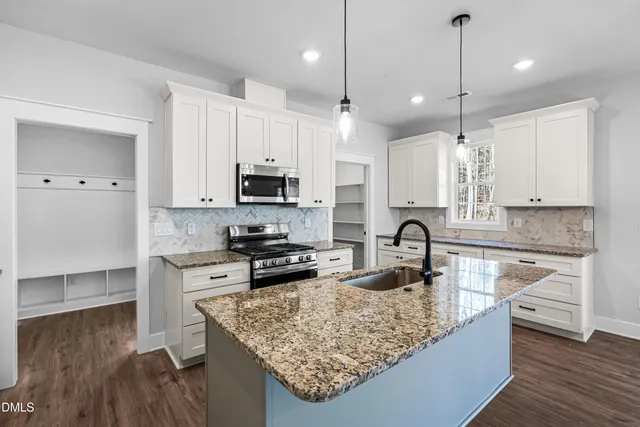 a kitchen with kitchen island granite countertop a sink stove and refrigerator