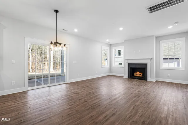 a view of an empty room with wooden floor fireplace and a window