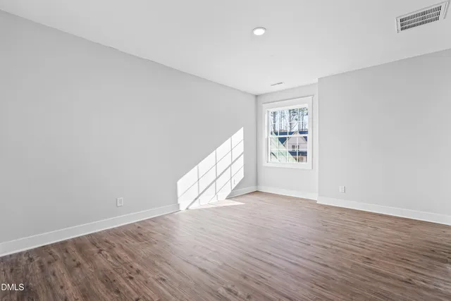 a view of an empty room with window and wooden floor