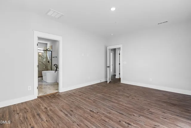 an empty room with wooden floor and a bathroom