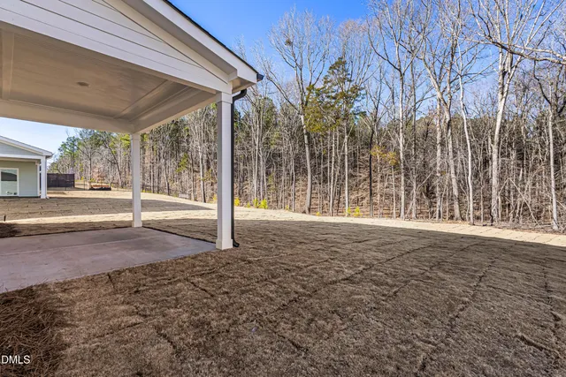 a view of a yard with porch and wooden fence