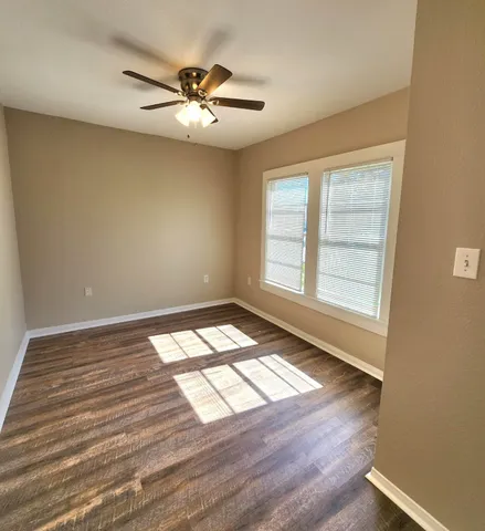a view of empty room with wooden floor and fan