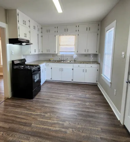 a kitchen with granite countertop a stove and cabinets