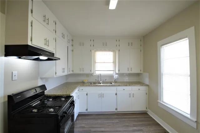 a kitchen with granite countertop a sink a stove and cabinets